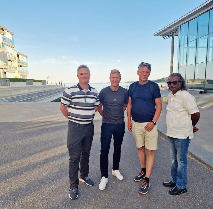 Kjell Helge Kleppestø, Kjetil Kristiansen, Steinar Evensen og Gideon Arulmani står foran Bølgen Kulturhus med sjøen bak seg